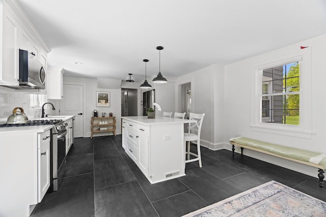 227 Sugar St, Newtown, CT 06470 - kitchen with appliances with stainless steel finishes, white cabinetry, a kitchen breakfast bar, a kitchen island, and a sink
