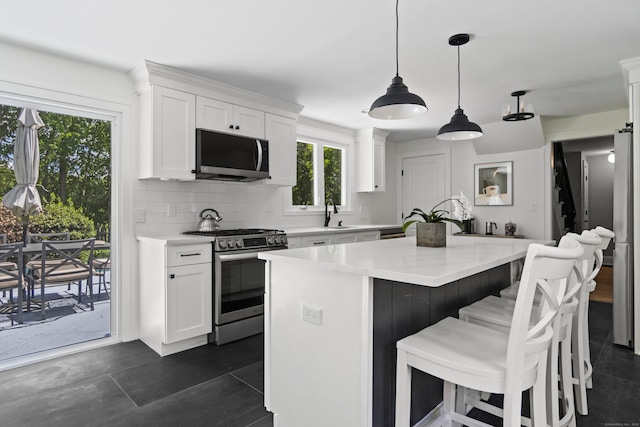 227 Sugar St, Newtown, CT 06470 - kitchen featuring appliances with stainless steel finishes, light countertops, decorative backsplash, white cabinets, and a breakfast bar area