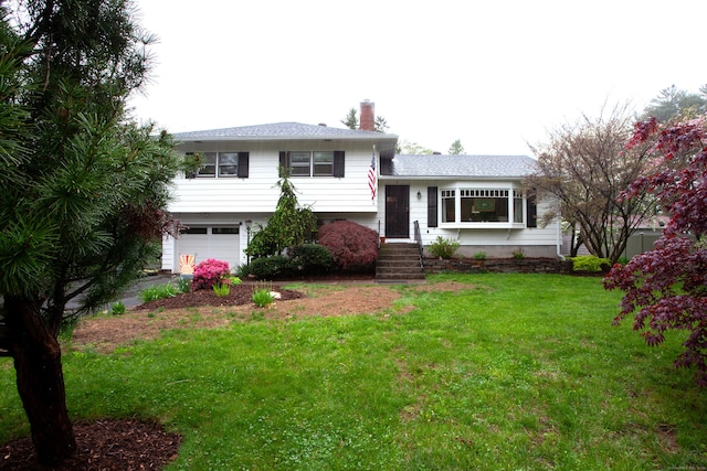 split level home with an attached garage, a chimney, and a front yard