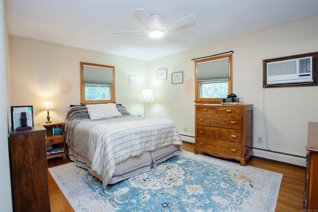 bedroom featuring a baseboard heating unit, multiple windows, a baseboard radiator, and wood finished floors