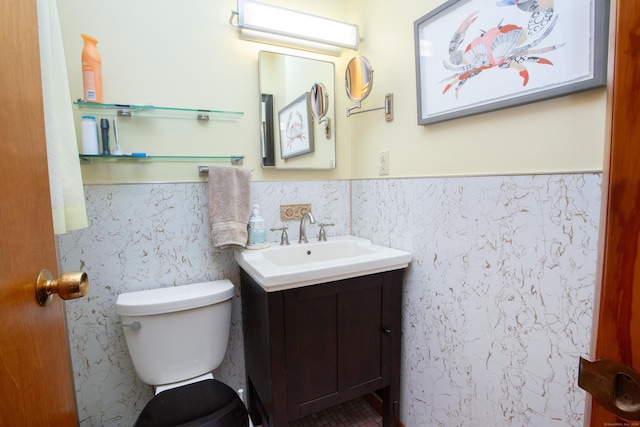 half bath featuring toilet, vanity, and wainscoting