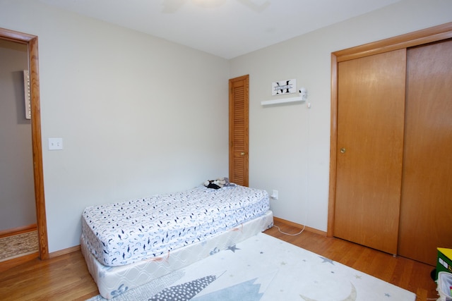 bedroom featuring baseboards, light wood-type flooring, and a closet