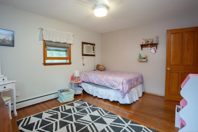 bedroom with an AC wall unit, a ceiling fan, baseboard heating, and wood finished floors