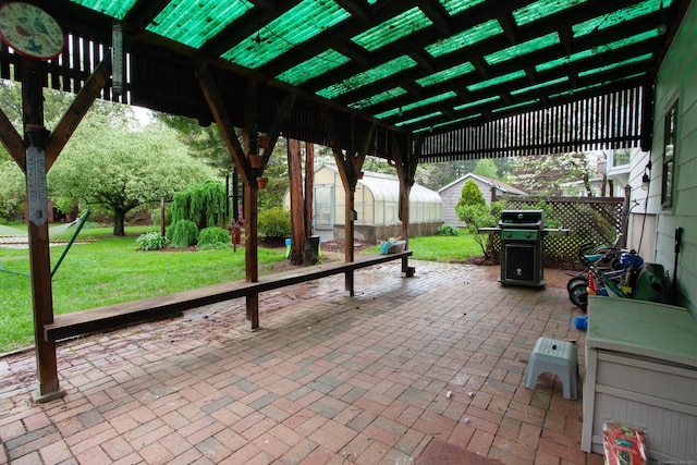 view of patio / terrace with an outdoor structure, a greenhouse, and a grill