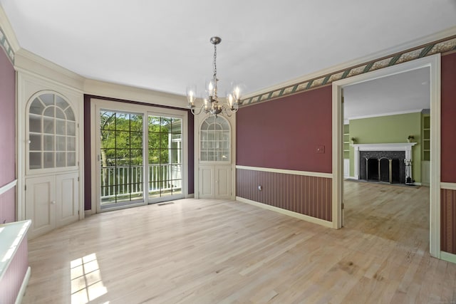 157 Pine Lake Rd, Westbrook, CT 06498 - unfurnished dining area featuring a chandelier, a wainscoted wall, a fireplace, light wood-style flooring, and a decorative wall