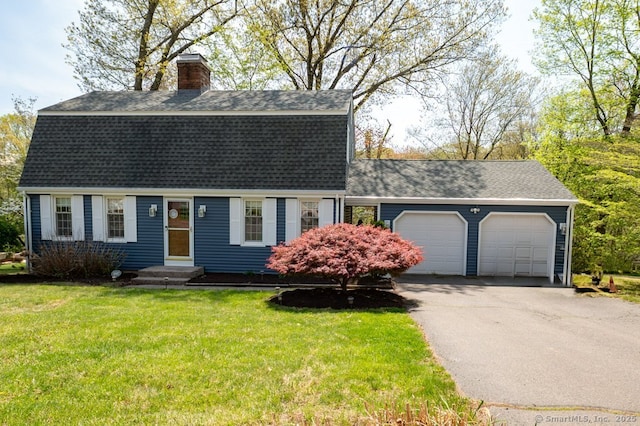 colonial inspired home with a shingled roof, a garage, asphalt driveway, a chimney, and a front yard