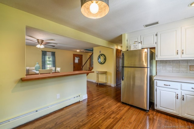 kitchen with freestanding refrigerator, a baseboard heating unit, white cabinetry, dark wood-style flooring, and tasteful backsplash