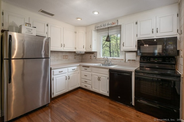 kitchen with black appliances, a sink, light countertops, white cabinetry, and recessed lighting
