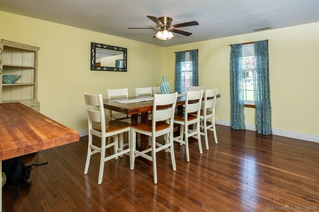 dining area featuring hardwood / wood-style floors, baseboards, a textured ceiling, and ceiling fan