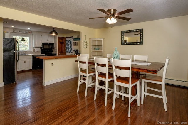dining room with dark wood finished floors, a ceiling fan, a textured ceiling, and a baseboard radiator