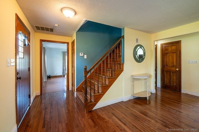 hallway with hardwood / wood-style flooring, a textured ceiling, stairs, and baseboards