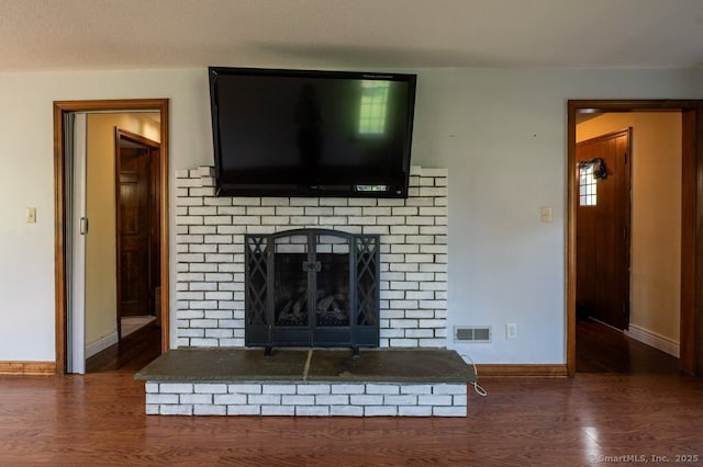detailed view of baseboards, wood finished floors, and a brick fireplace