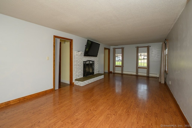 unfurnished living room featuring a textured ceiling, light wood finished floors, a brick fireplace, baseboards, and baseboard heating