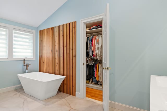 6 Shadow Ln, Norwalk, CT 06851 - bathroom featuring lofted ceiling, a soaking tub, a spacious closet, marble look tiles, and baseboards