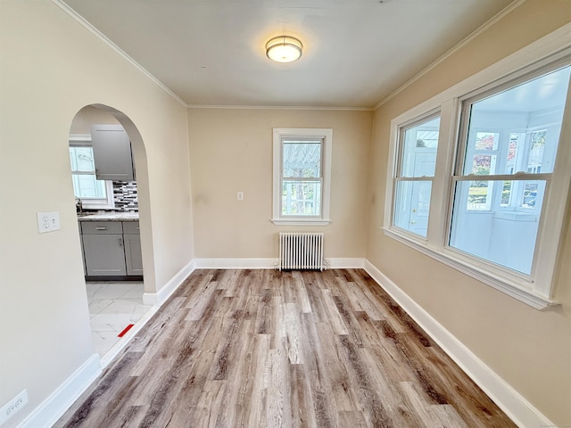 815 Alling Rd, Orange, CT 06477 - unfurnished dining area featuring radiator heating unit, light wood-type flooring, arched walkways, crown molding, and baseboards
