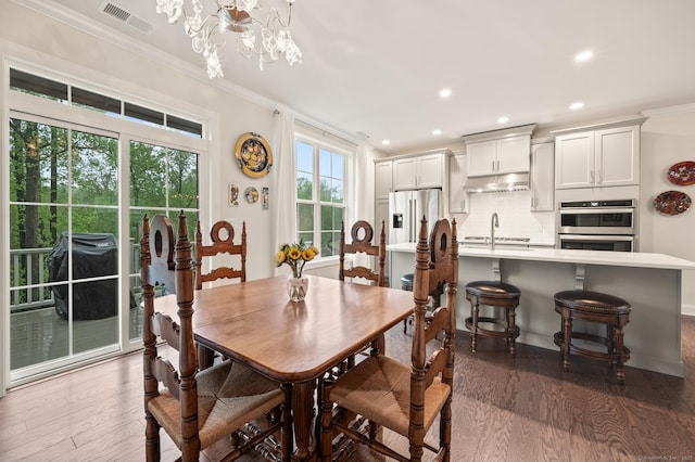 dining room with a chandelier, crown molding, wood finished floors, recessed lighting, and baseboards