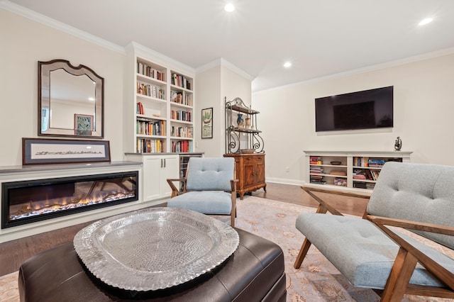 sitting room featuring a glass covered fireplace, ornamental molding, recessed lighting, baseboards, and wood finished floors