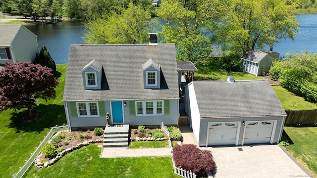 view of front of house with a water view, a chimney, driveway, and an outbuilding