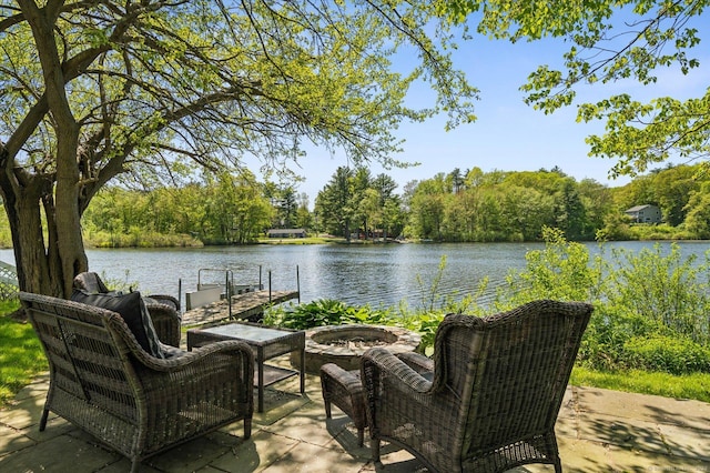 view of patio / terrace featuring an outdoor fire pit, a water view, and a boat dock