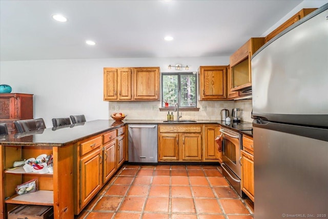 6 Kristy Dr, Bethel, CT 06801 - kitchen featuring appliances with stainless steel finishes, a peninsula, brown cabinetry, dark countertops, and decorative backsplash
