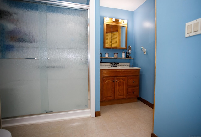 bathroom featuring vanity, baseboards, and a shower stall