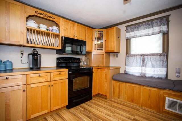 kitchen with glass insert cabinets, crown molding, light wood-type flooring, visible vents, and black appliances