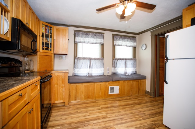 kitchen featuring glass insert cabinets, light wood finished floors, ceiling fan, visible vents, and black appliances