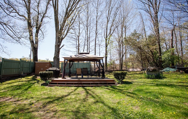 view of yard with an outbuilding, fence, a gazebo, a wooden deck, and a storage unit