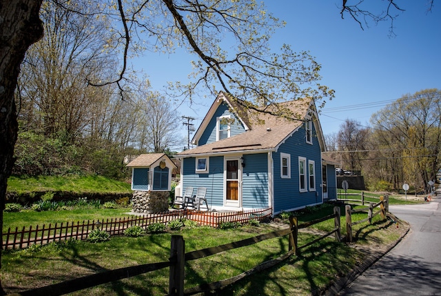 view of front of home featuring fence private yard, a shingled roof, and a front lawn