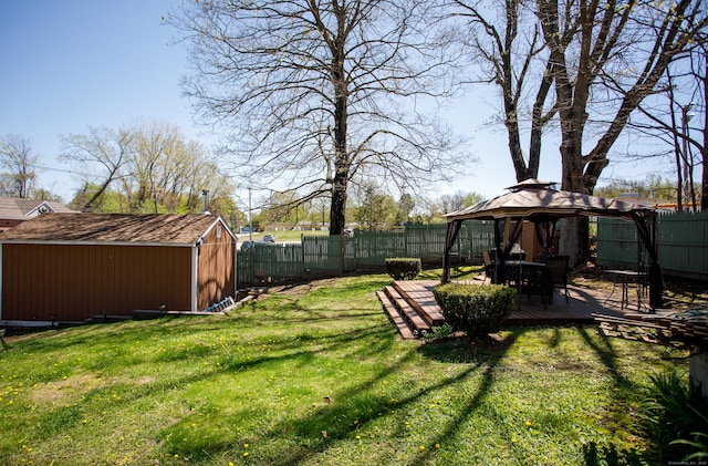 view of yard featuring a gazebo, a wooden deck, a fenced backyard, and a storage unit
