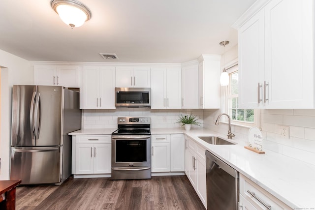 26 Sharon Cir, Meriden, CT 06450 - kitchen featuring appliances with stainless steel finishes, white cabinetry, light countertops, dark wood finished floors, and decorative backsplash