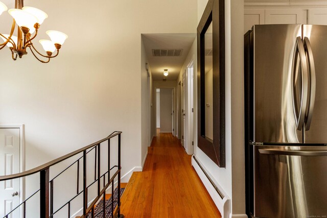 26 Sharon Cir, Meriden, CT 06450 - hall featuring a baseboard radiator, light wood-style floors, a chandelier, and an upstairs landing