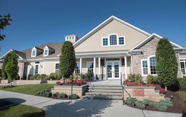 view of front of home with a porch, french doors, and stone siding