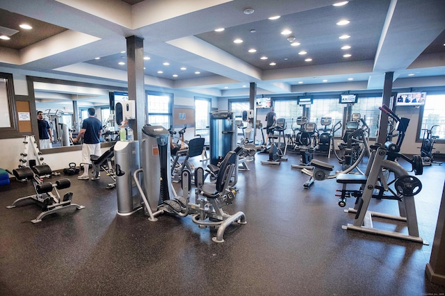 gym with a tray ceiling, ornate columns, and a healthy amount of sunlight