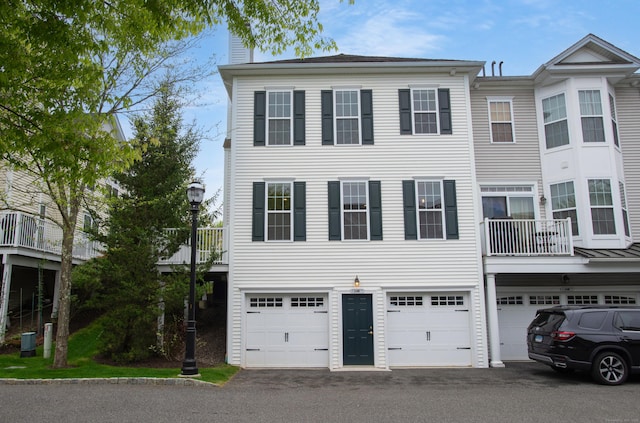 view of property featuring a garage, a chimney, and driveway