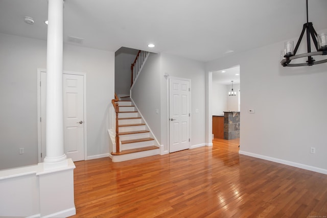 unfurnished living room featuring wood finished floors, a notable chandelier, stairway, baseboards, and recessed lighting