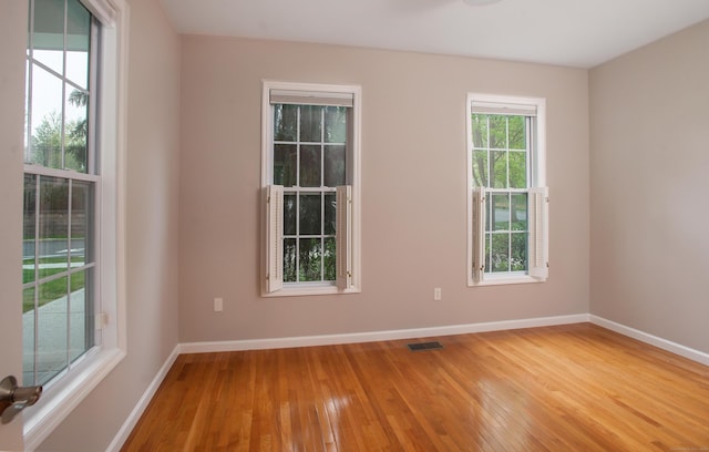 spare room with hardwood / wood-style flooring, baseboards, and visible vents