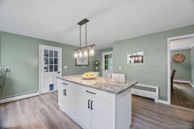 kitchen featuring radiator, a baseboard heating unit, wood finished floors, and white cabinets