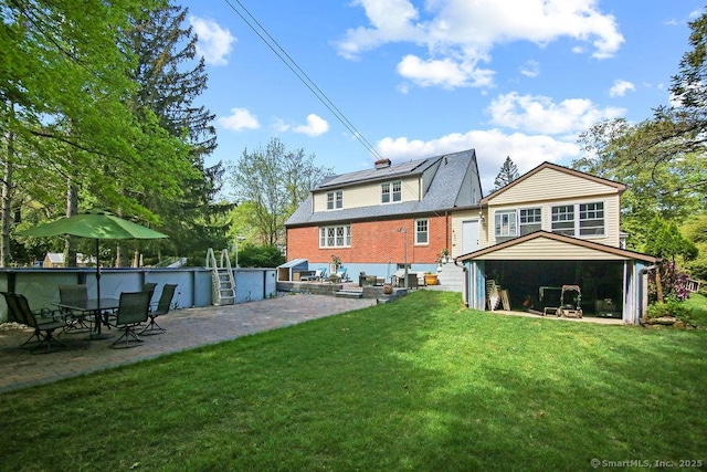 rear view of house featuring a patio, a lawn, and brick siding