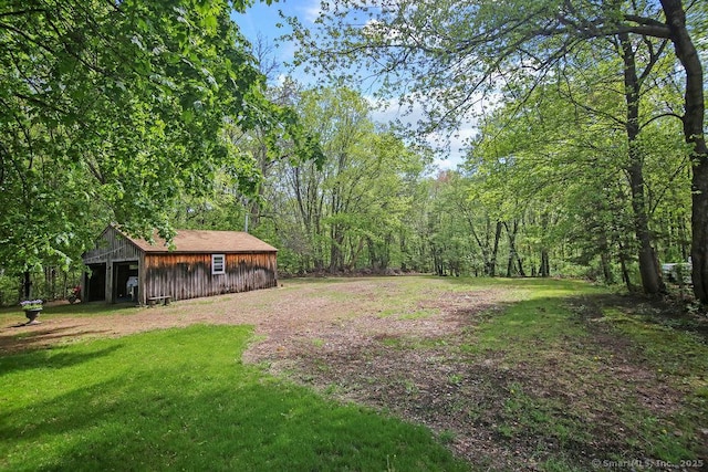 view of grassy yard featuring an outdoor structure, a view of trees, and a pole building