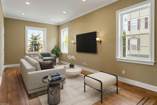 living room featuring baseboards, wood finished floors, ornamental molding, and recessed lighting