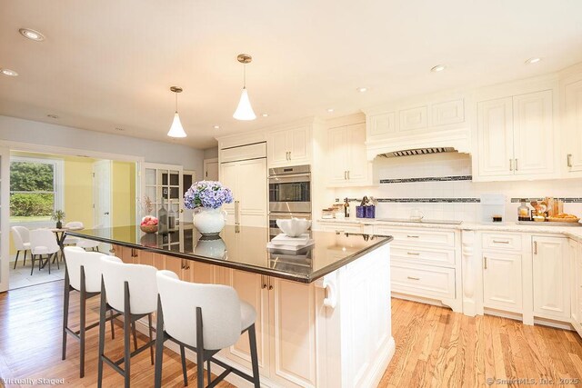 17 Grays Farm Rd, Weston, CT 06883 - kitchen featuring stainless steel double oven, light wood-type flooring, a kitchen bar, backsplash, and a center island