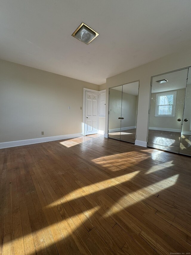 135 Lambert Ave, Meriden, CT 06451 - unfurnished bedroom featuring dark wood-style flooring, baseboards, and two closets