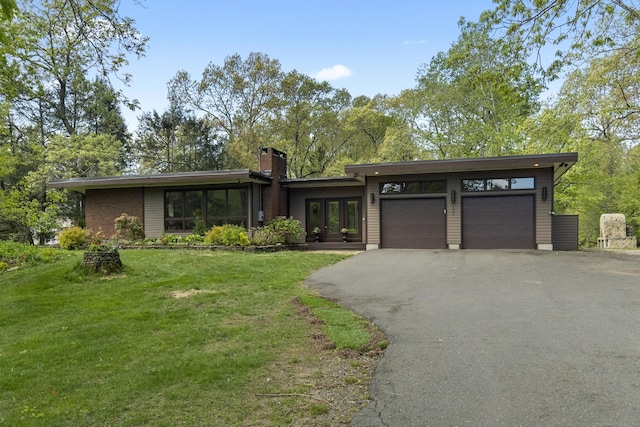 192 Thompson Hill Rd, Portland, CT 06480 - mid-century home with asphalt driveway, a front lawn, a chimney, an attached garage, and french doors
