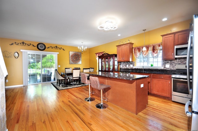 kitchen featuring appliances with stainless steel finishes, a kitchen island, a chandelier, light wood-style flooring, and recessed lighting