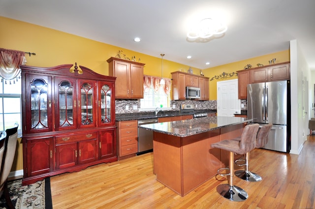 kitchen with stainless steel appliances, a kitchen island, backsplash, light wood finished floors, and recessed lighting
