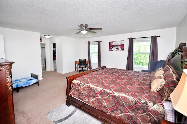 bedroom with carpet floors, multiple windows, a textured ceiling, and a ceiling fan
