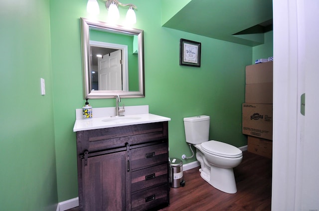 bathroom featuring toilet, vanity, wood finished floors, and baseboards