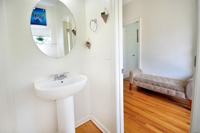 bathroom with wood finished floors, baseboards, and a sink