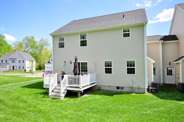 rear view of property with a yard, a deck, and central AC